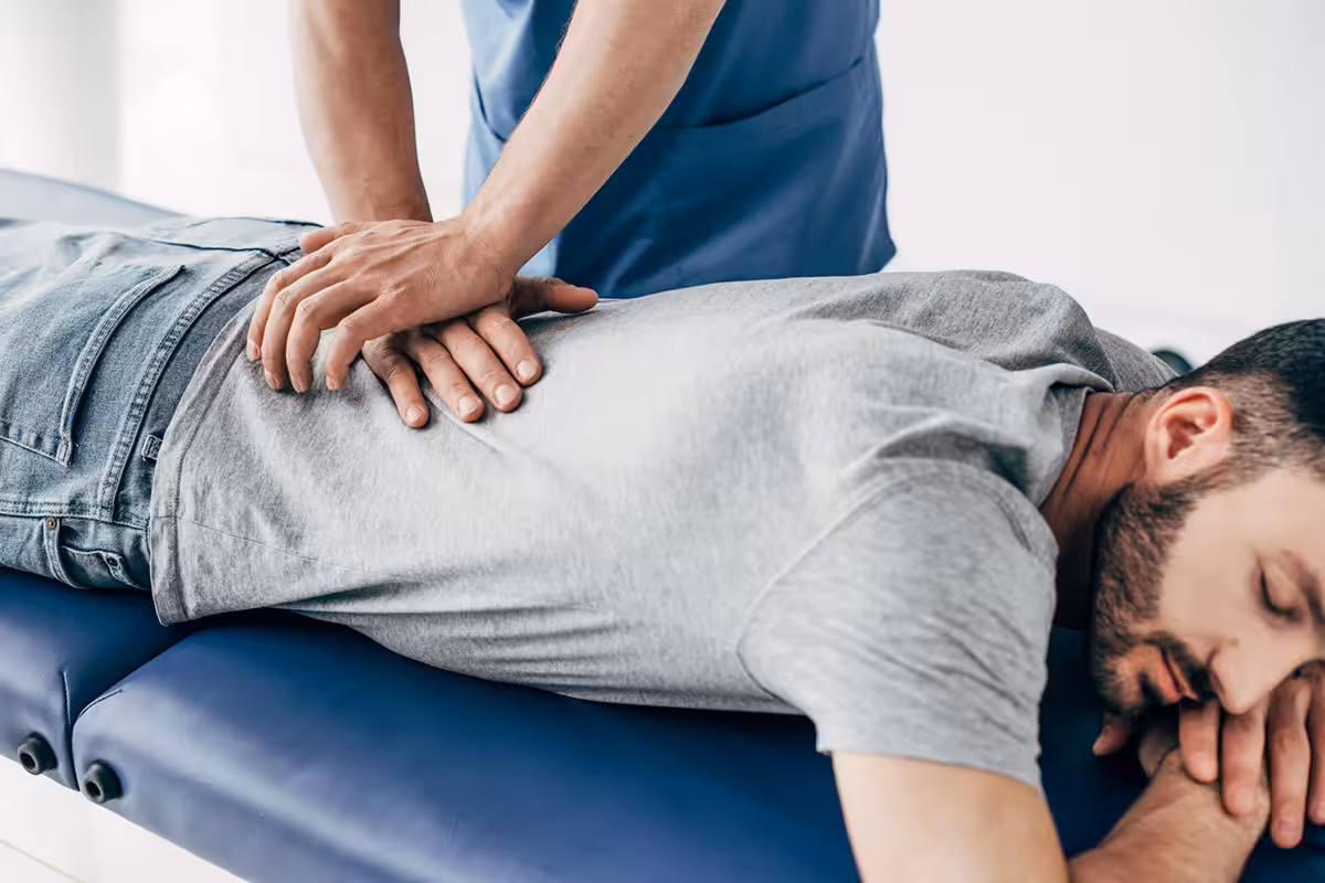 Chiropractor applying spinal manipulation to a patient's lower back during a clinical treatment session
