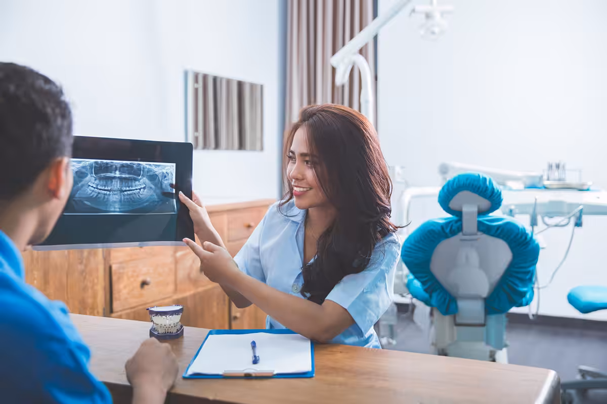 Dental professional reviewing panoramic X-ray with patient during consultation at modern Alberta dental clinic