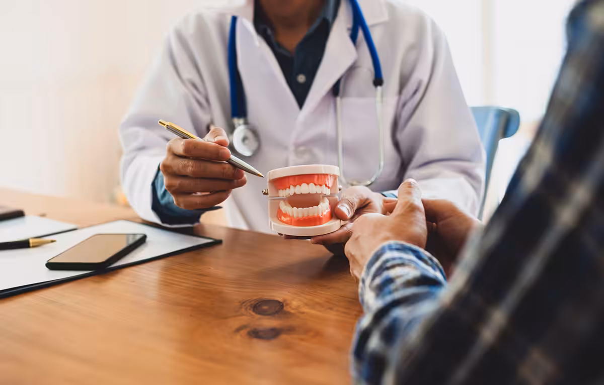 Dentist pointing to a dental jaw model while reviewing a restorative treatment plan with a patient at a desk