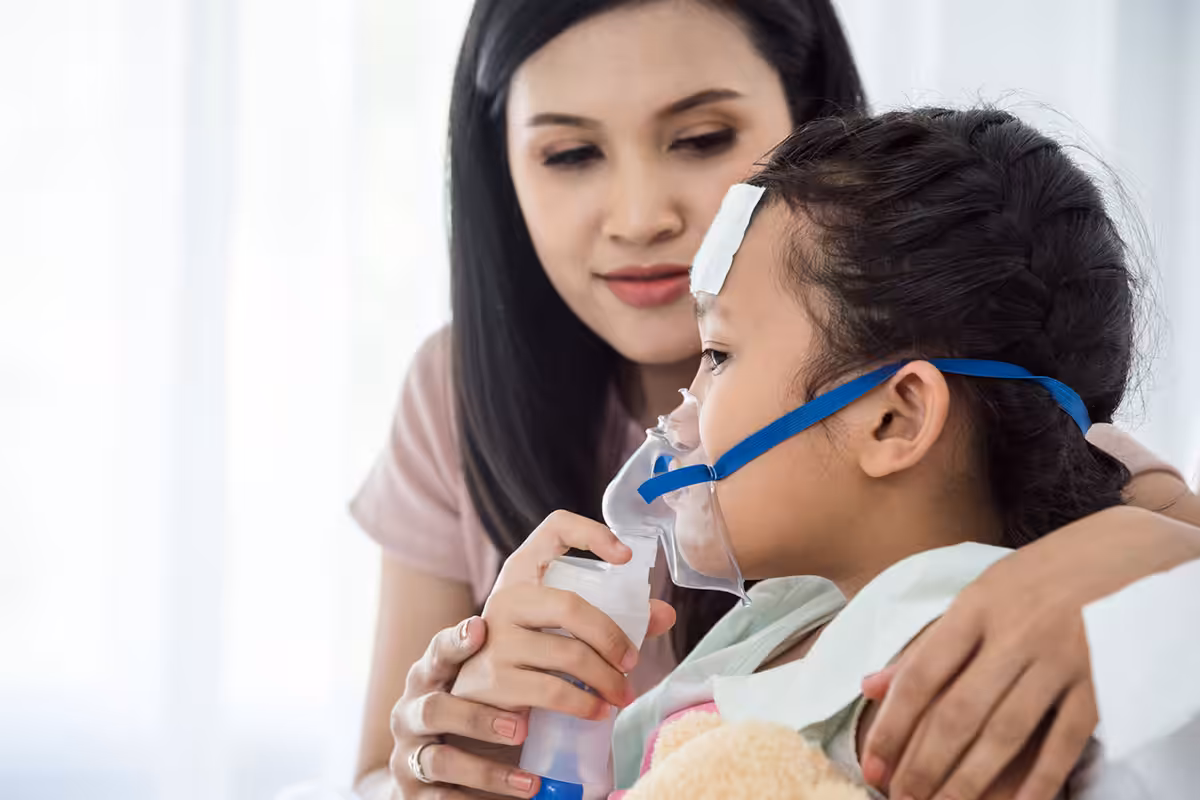 Child using oxygen nebulizer mask with parent's support during medical treatment covered by ASEBP retirement health benefits