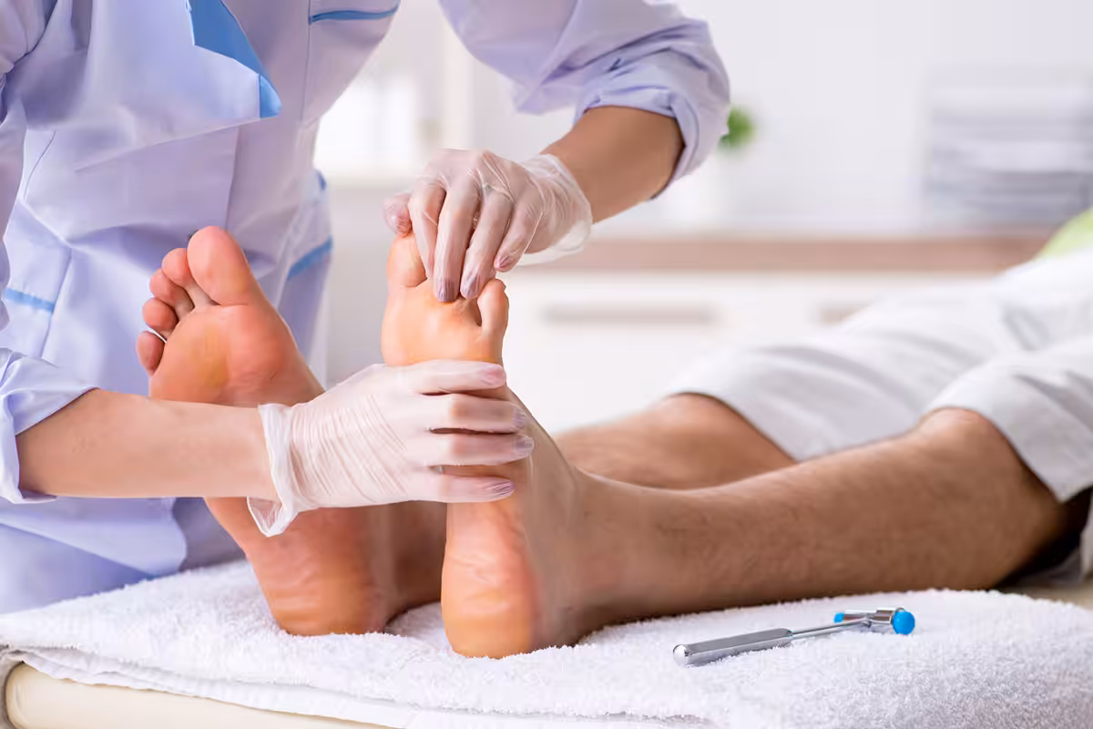 Podiatrist in white coat and gloves examining patient's feet at a chiropody clinic in Alberta