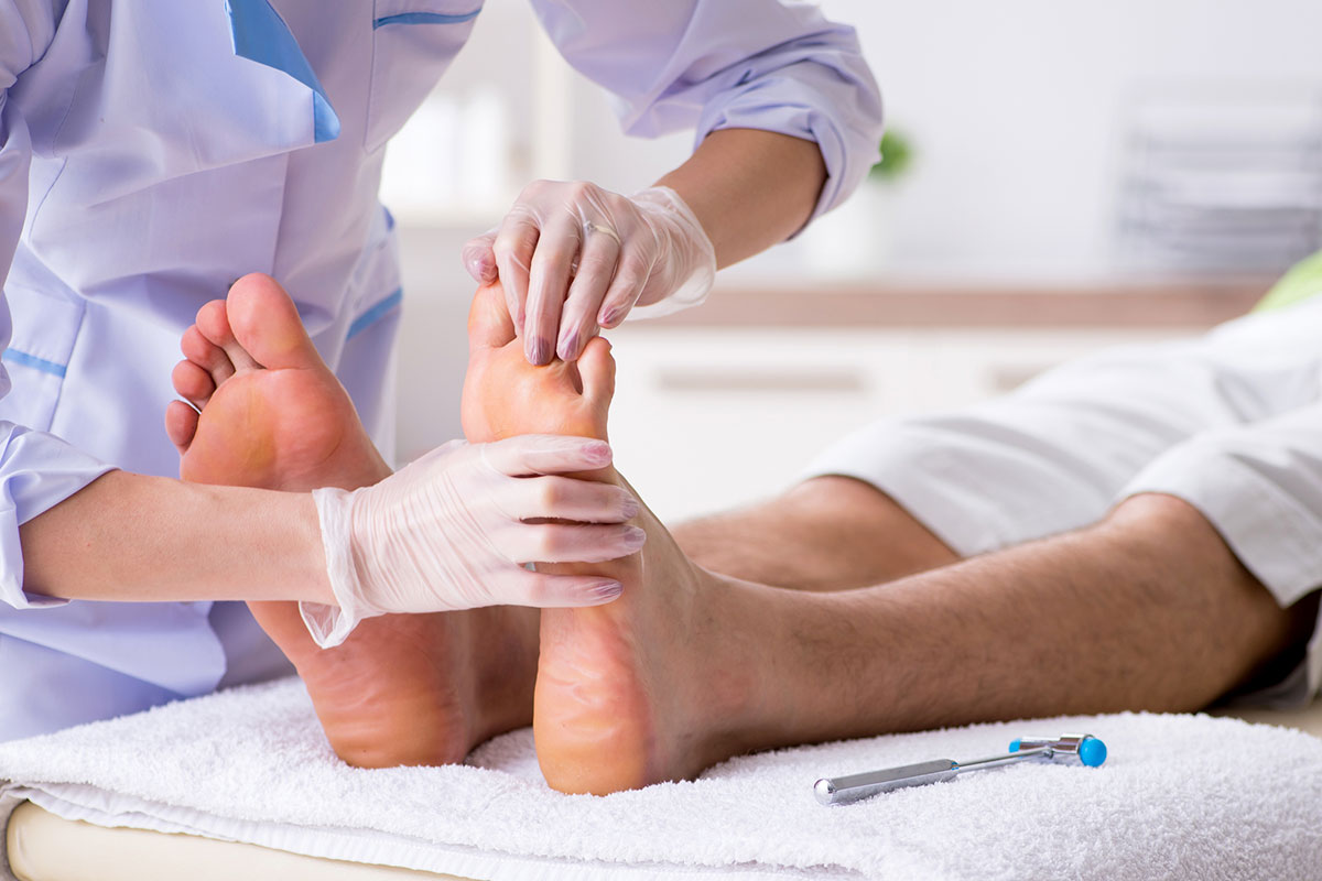 Podiatrist in white coat and gloves examining patient's feet at a chiropody clinic in Alberta