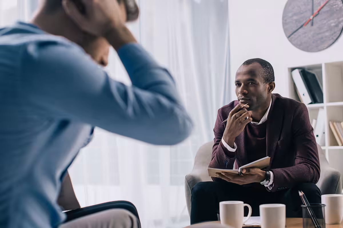 Psychologist attentively listening to a patient during a counselling session in a professional office setting