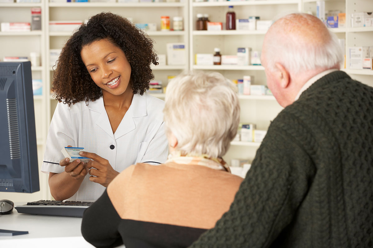 Retired couple consulting pharmacist about maintenance medication program and prescription drug coverage