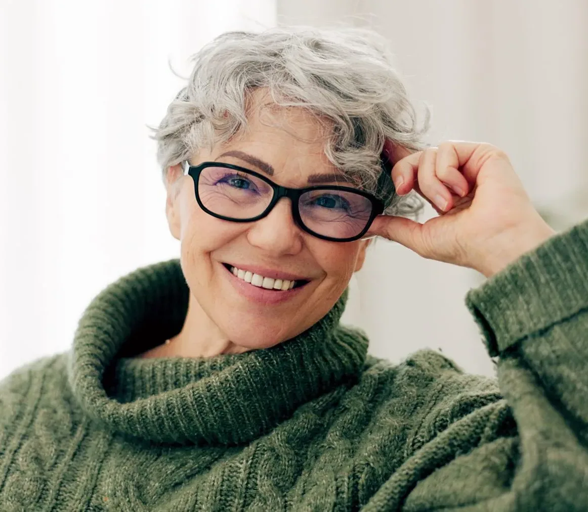 Smiling retired Alberta educator adjusting glasses, representing ASEBP MyRetiree Plan members at retirement events